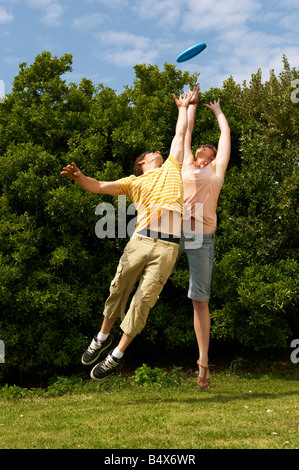 Couple de sauter pour attraper un frisbee Banque D'Images