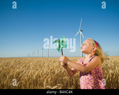 Girl holding pinwheel on wind farm Banque D'Images