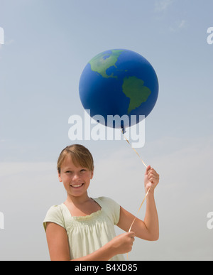 Girl holding globe balloon Banque D'Images