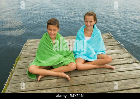 Enfants enveloppés dans des serviettes sur dock Banque D'Images