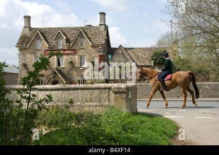 Cheval et cavalier traversant un pont de pierre sur la rivière Colne dans le village de Cotswold SOUTH CERNEY, CIRENCESTER, Gloucestershir Banque D'Images