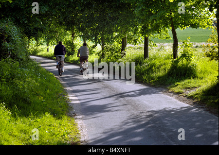 Deux hommes à vélo sur route de campagne tranquille Norfolk Angleterre Broome Banque D'Images