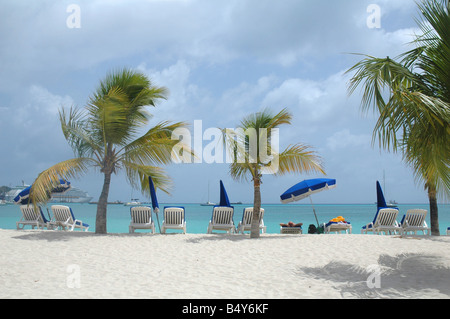 Beau billet tourné d'une rangée de chaises de plage et parasols aucun peuple sur la plage à saint Martin avec bateau de croisière en arrière-plan Banque D'Images