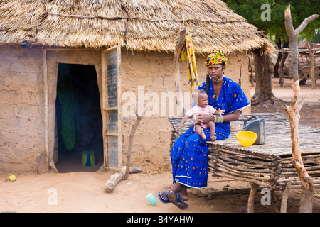 Une femme peule dans un village dans le sud-ouest du Niger se trouve en face de sa maison avec un bébé Banque D'Images