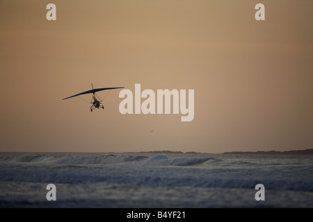Microlite voler au-dessus de la mer à la plage de White Rocks dans portrush au coucher du soleil l'Irlande du Nord Banque D'Images