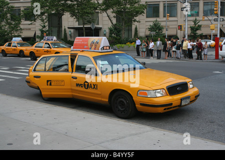 Un taxi jaune de New York City au bord du trottoir avec d'autres taxis à l'arrière-plan dans l'Upper West Side de Manhattan Banque D'Images