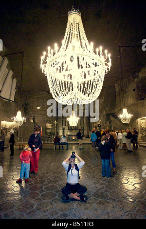 Les touristes dans la Chapelle St Cunégonde du sel de Wieliczka à Cracovie sous un énorme lustre taillée dans le sel gemme. Banque D'Images