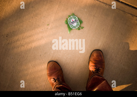 Close up of a man s pieds à côté d'une bouteille de bière brisée PARUTION MODÈLE Banque D'Images