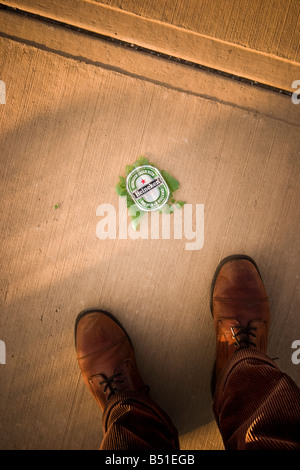 Close up of a man s pieds à côté d'une bouteille de bière brisée PARUTION MODÈLE Banque D'Images