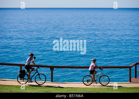 Senior couple on mountain bikes suivi, le vélo le long de l'océan en Australie au point Danger, Coolangatta. Banque D'Images
