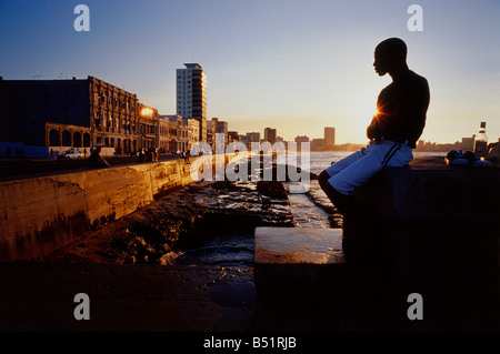 Homme assis en mer au coucher du soleil Malicon, La Havane, Cuba Banque D'Images