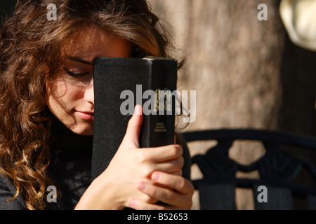 Young woman holding Bible et prier à l'extérieur close up Banque D'Images