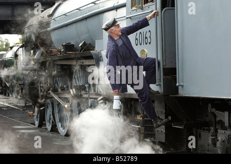 Un moteur à vapeur conducteur monte dans sa cabine. Le train est 60163 tornade, sur la Great Central Railway. Banque D'Images