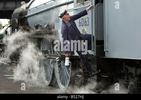 Un moteur à vapeur conducteur monte dans sa cabine. Le train est 60163 tornade, sur la Great Central Railway. Banque D'Images
