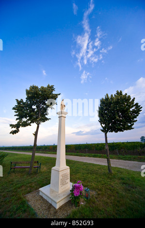 Statue de Saint Mary à côté d'une route de campagne contre un ciel bleu clair. Banque D'Images