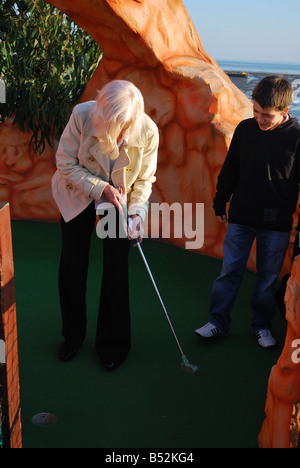 SENIOR CITIZEN JOUER MINI GOLF AVEC jeune garçon Banque D'Images