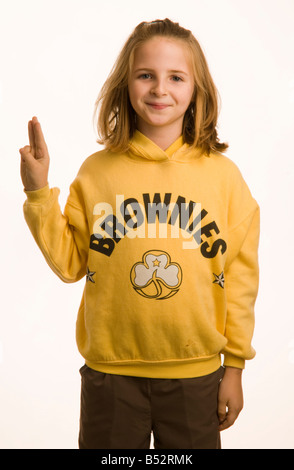 10 ans, fille, vêtue de son uniforme de Brownies donnant le salut à trois doigts, UK Banque D'Images