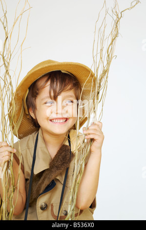 Mixed Race boy dans safari outfit holding branches Banque D'Images