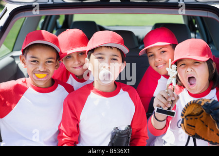 Les garçons multi-ethnique au baseball uniforms making faces et holding trophy Banque D'Images