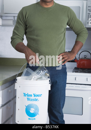 Mixed Race man holding benne de recyclage dans la cuisine Banque D'Images