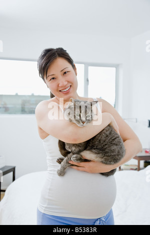 Pregnant Asian woman holding cat Banque D'Images