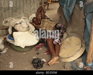 Les enfants esclaves au Bénin Afrique de l'Ouest Février 2007 dans une cabane sombre à côté du marché intérieur éclairé par la faible lumière du soleil passer à travers le toit de tôle fissuré 12 ans Alice de son rouses sommeil agité sur un tas de chiffons et explique comment elle est arrivée ici à Cotonou Bénin s plus grande ville après ses parents vendue à un trafiquant Alice et 24 autres passé huit jours dans une fuite d'un canoë avec rien d'autre que de manger la farine sèche avant d'arriver ici au Dan Tokpa marché à travailler pour rien à nuits, elle fait de son mieux pour éviter les criminels et les toxicomanes qui rôdent le rat est encombré de la plus tragiquement Banque D'Images