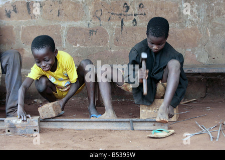 Les enfants esclaves au Bénin Afrique de l'Ouest Février 2007 huit ans de travaux forcés et Benson Edoh 9 sont mis au travail pour 12 heures par jour comme exténuante metal, cachée dans un coin de ce marché et tentaculaire des garçons de cinq peinent dans la chaleur latente avant de voir les visages de ces malheureux enfants que vous entendrez le son de leur esclavage la clameur des marteaux en plomb lourd sur des feuilles de métal nu et ces jeunes ont été vendus pour seulement 10 par leurs parents pour les trafiquants d'enfants qui les vendent sur de travailler sans rémunération et sans espoir dans un Mamoutche avilissante de misère Banque D'Images