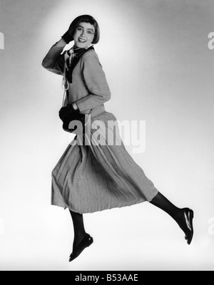 Fashion - Costumes noir et blanc Prince de Galles vérifier jupe plissée longue et veste assortie. Femme modèle saute en l'air. Aussi le port de collants noirs, des gants et des chaussures. Octobre 1986 P017852 Banque D'Images