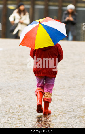 Un jour de pluie à Londres , jeune fille enfant marche dans la pluie avec parapluie et bottes multicolore Banque D'Images