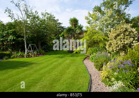 Grande pelouse avec rayures cordyline et courbant sentier de gravier. Banque D'Images