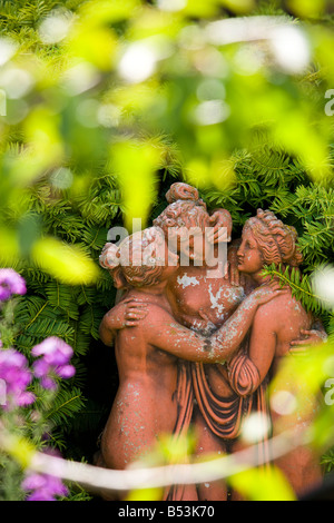 Statue en terre cuite de trois femmes par une haie d'If Banque D'Images