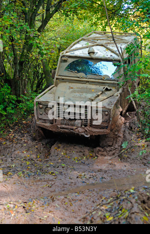 Land Rover Defender 110 boueux en passant par la boue profonde sur une piste forestière dans le Weserbergland. Banque D'Images