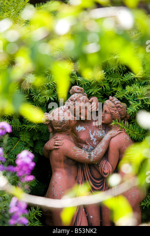 Statue en terre cuite de trois femmes par une haie d'If Banque D'Images