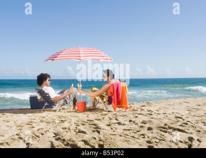Multi-ethnic couple relaxing at beach Banque D'Images