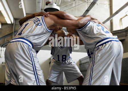 Les joueurs de basket-ball multi-ethnique se blottissent dans vestiaire Banque D'Images