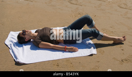 Jeune femme sur une serviette de bain de soleil sur la plage, Rhossili Beach, péninsule de Gower, au Pays de Galles, en Grande-Bretagne, en Europe Banque D'Images