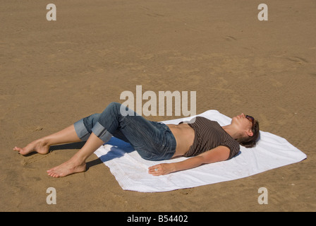 Jeune femme sur une serviette de bain de soleil sur la plage, Rhossili Beach, péninsule de Gower, au Pays de Galles, en Grande-Bretagne, en Europe Banque D'Images