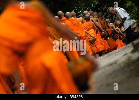 Les moines font leurs rondes quotidiennes pour recevoir l'aumône d'adeptes du bouddhisme à LuangPrabang Banque D'Images