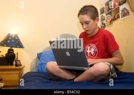 Fatigué à la Teenage boy en utilisant un ordinateur portable dans sa chambre la nuit Banque D'Images