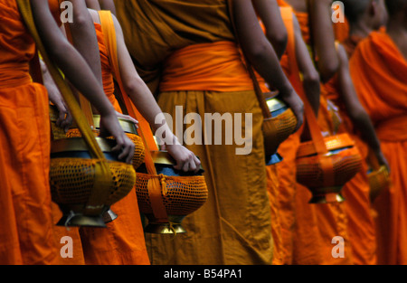 Les moines font leurs rondes quotidiennes pour recevoir l'aumône d'adeptes du bouddhisme à LuangPrabang Banque D'Images