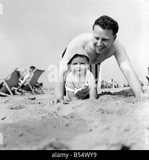 Neuf mois Paul Kemshell de ramper sur le sable à Rhyl avec son papa Monsieur Brian Kemshell de Muro. Juin 1960 M4315-004 Banque D'Images