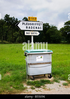 Poubelle communale à côté de la route dans la France rurale à côté d'un panneau routier local Banque D'Images