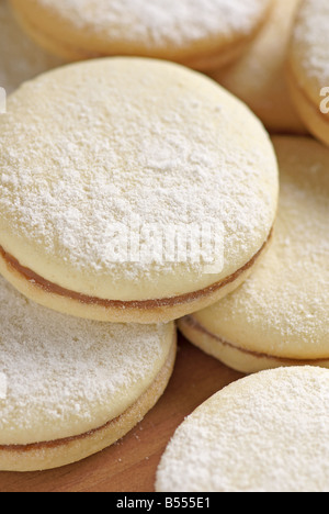 Alfajores de maïzena (sud-américain cookies beurre farci de dulce de leche) sur une plaque de bois Banque D'Images