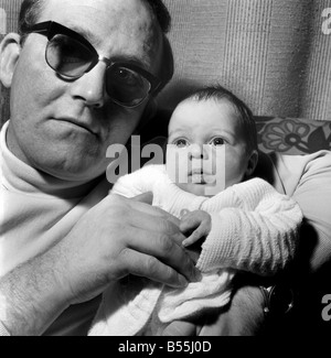 Famille : père tenant son enfant nouveau-né à leur maison. Décembre 1969 Z12116-001 Banque D'Images