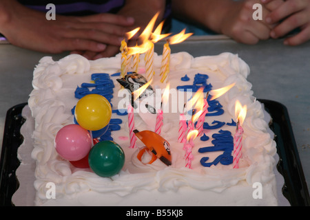 Gâteau d'anniversaire avec des bougies, des mains des enfants attendent patiemment Banque D'Images