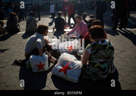 Les consommateurs et leurs achats de Macys prenez une pause dans l'Union Square Park à New York Banque D'Images