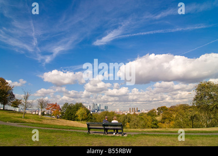 Grand angle horizontal de gens assis sur un banc, profitant de la vue depuis le haut de Greenwich Park au soleil Banque D'Images