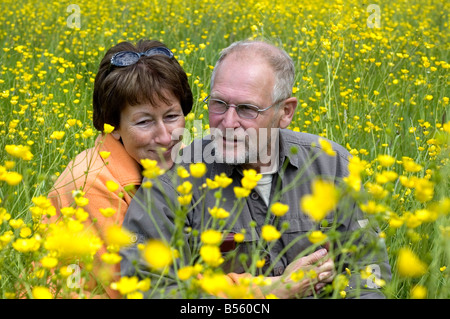 Joli couple senoir profiter du soleil dans un champ d'herbe verte pleine de renoncules Banque D'Images