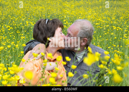 Joli couple senoir profiter du soleil dans un champ d'herbe verte pleine de renoncules Banque D'Images