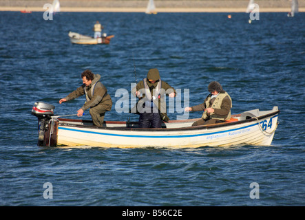 Trois hommes dans un bateau de pêche sur une journée ensoleillée. Format paysage Banque D'Images